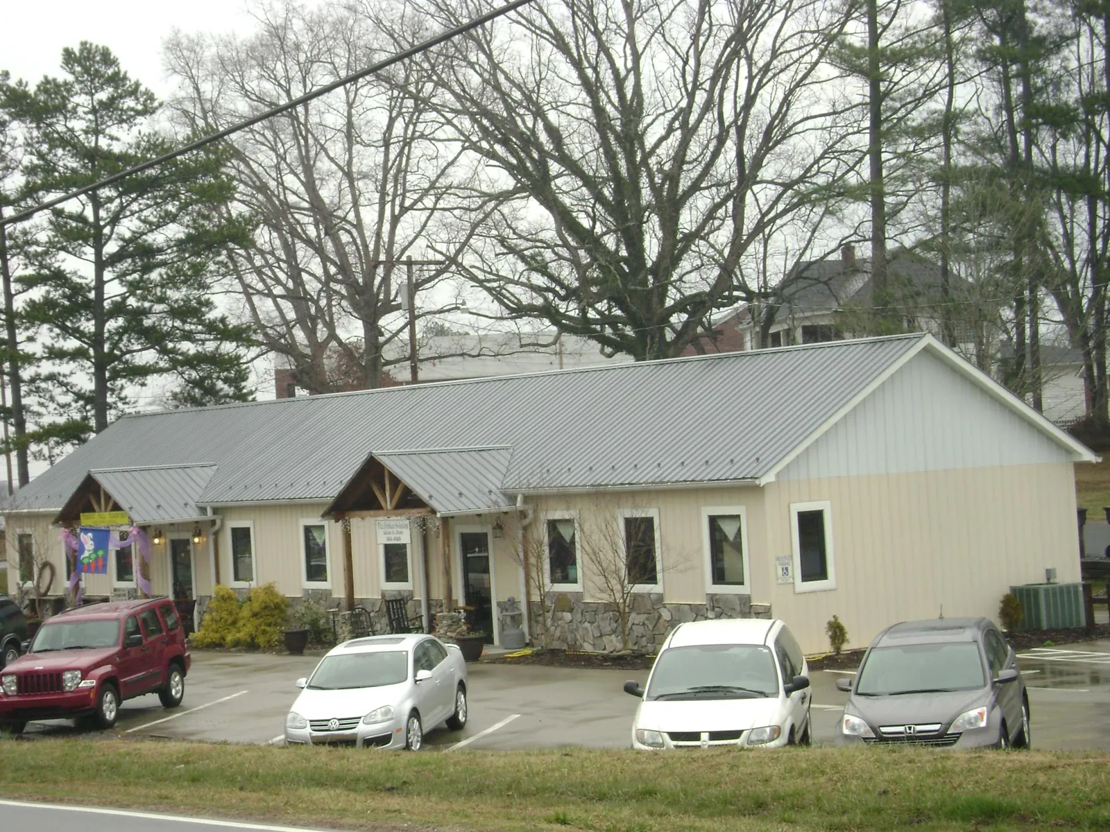 Gray metal roof with timber entry brackets on a small commercial building in Gaston