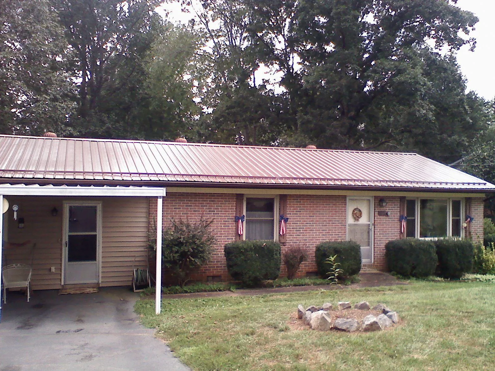 Bronze metal roof and carport on a brick ranch home — Roof Repair work by our crew in Gaston